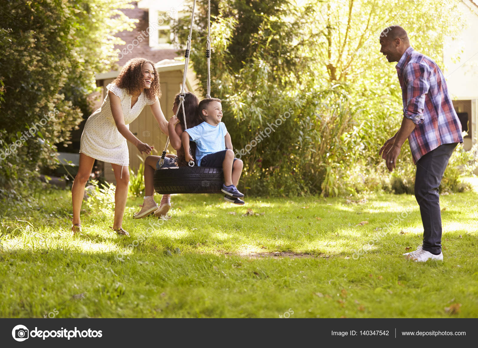Padres e hijos en el columpio de neumáticos: fotografía de stock