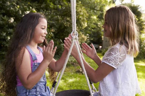 Dos niñas jugando en neumático swing — Foto de Stock