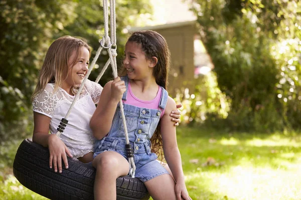 Due ragazze sedute su pneumatico swing — Foto Stock