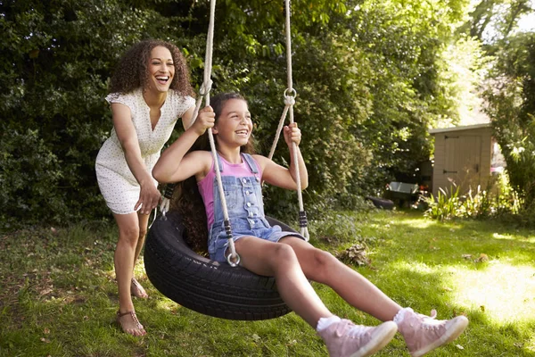 Madre e figlia seduta su pneumatico swing — Foto Stock