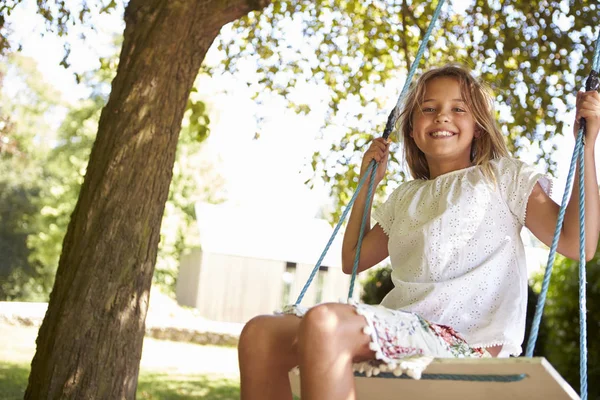 Mladá dívka si hraje na pneumatiky Swing v zahradě — Stock fotografie