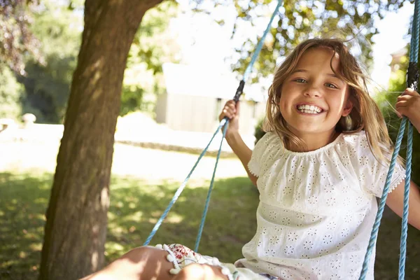 Junges Mädchen spielt auf Reifenschaukel im Garten — Stockfoto