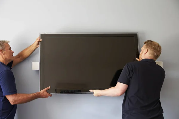 Männer montieren Fernseher an Wand — Stockfoto