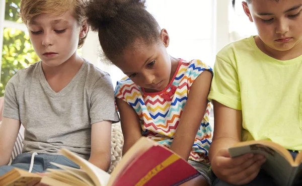 Bambini che leggono sul sedile della finestra — Foto Stock