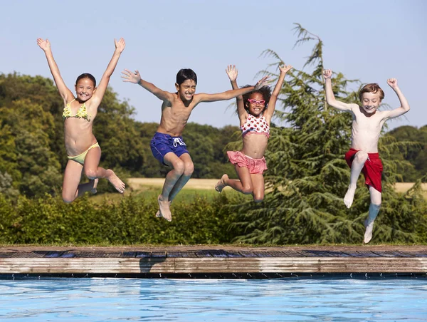 Lapset hyppäävät uima-altaaseen — kuvapankkivalokuva