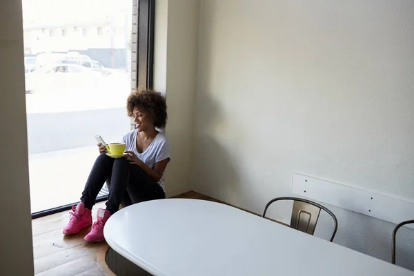 Junge Frau sitzt und nutzt Smartphone — Stockfoto