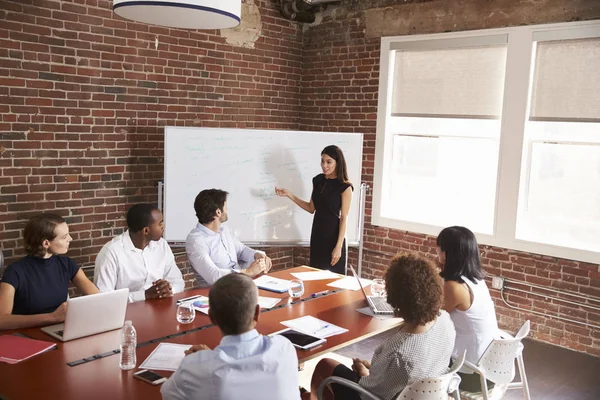 Junge Geschäftsfrau steht gegen Whiteboard — Stockfoto