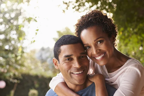 Jeune couple piggybackking dans le jardin — Photo