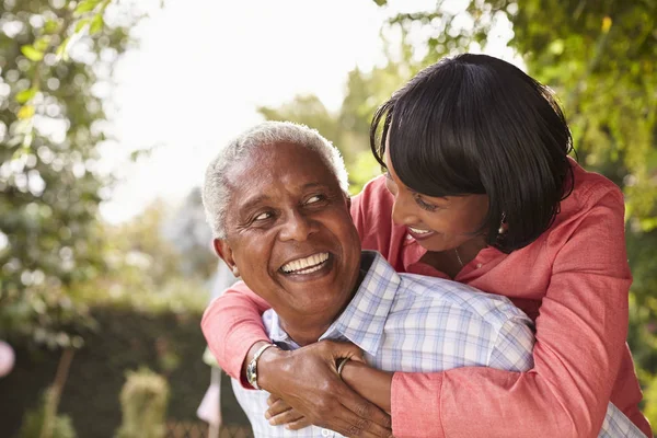 Senior pareja piggybacking en jardín — Foto de Stock