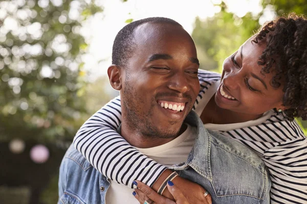 Jovem casal piggybacking no jardim — Fotografia de Stock