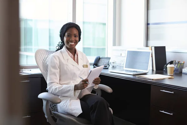 Femme médecin assis et souriant à la caméra — Photo