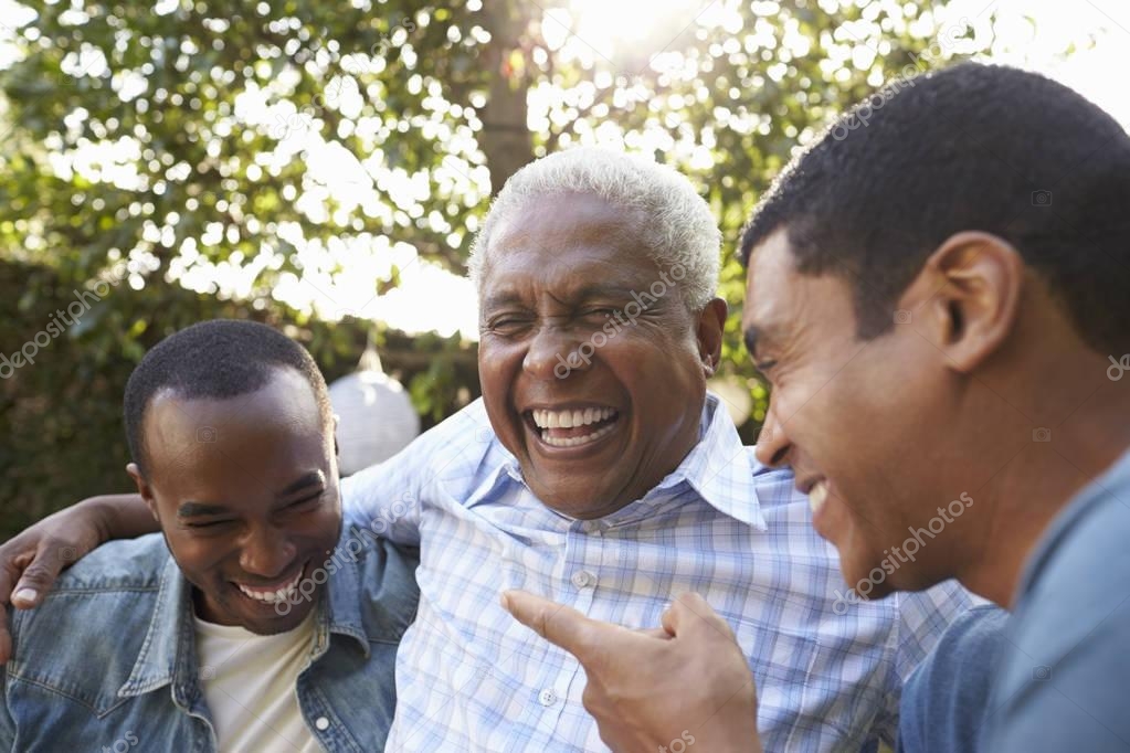 Happy senior african american man with adult sons in garden