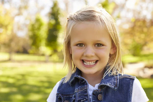Menina loira no parque sorrindo para a câmera — Fotografia de Stock