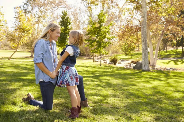 Mãe e filha jovem conversando em um parque, comprimento total — Fotografia de Stock