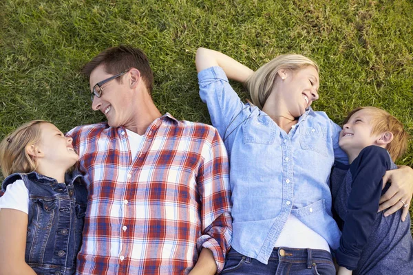 Familie liggen in park — Stockfoto