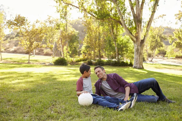 Батько і син відпочивають з футбольним м'ячем у парку — стокове фото