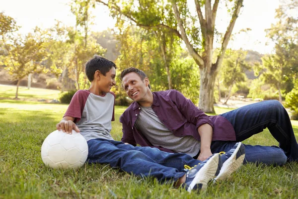 Pai e filho relaxando na grama — Fotografia de Stock