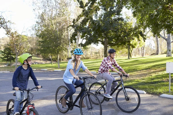 Padres e hijo en bicicleta por el parque — Foto de Stock