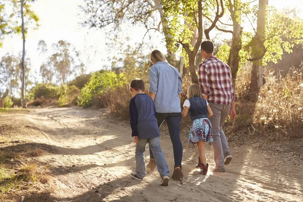 Jovem família caminhando à luz do sol — Fotografia de Stock