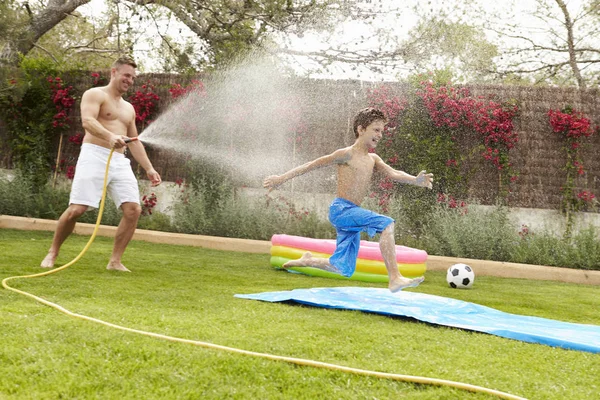 Father Spraying Son With Garden Hose — Stock Photo, Image