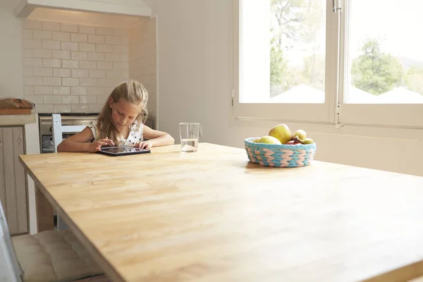 Молодая девушка за кухонным столом — стоковое фото