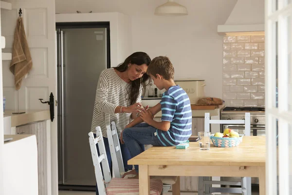 Madre poniendo yeso en brazo de hijo — Foto de Stock