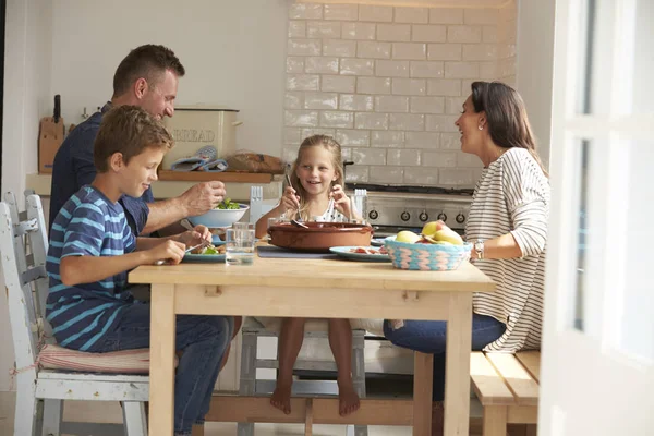 Семья сидит за столом и ест — стоковое фото