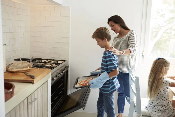Madre y niños horneando en horno — Foto de Stock