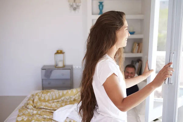 Woman opening window in room — Stock Photo, Image