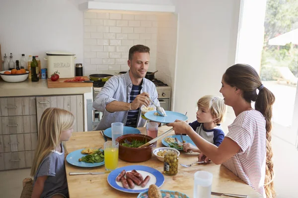 太陽に照らされた部屋のテーブルで食べる家族 — ストック写真