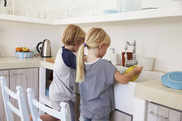Дети моют посуду на кухне — стоковое фото