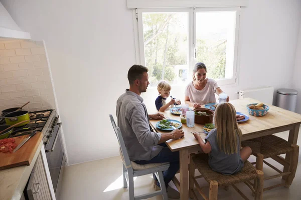 Família comendo à mesa no quarto iluminado pelo sol — Fotografia de Stock