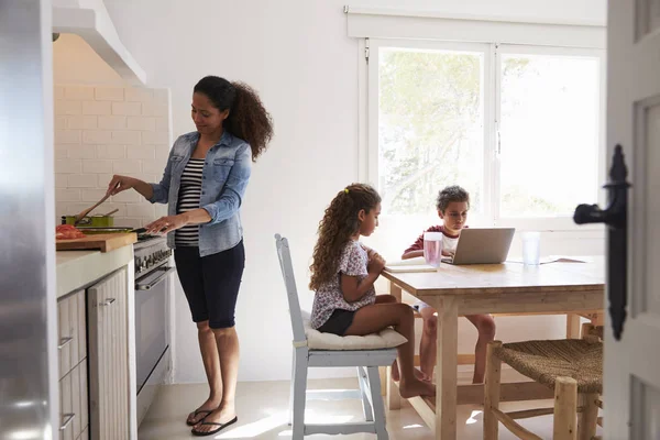 Mamá cocinando y los niños trabajando en la cocina — Foto de Stock