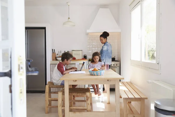 Mamma cucina e bambini che studiano in cucina — Foto Stock