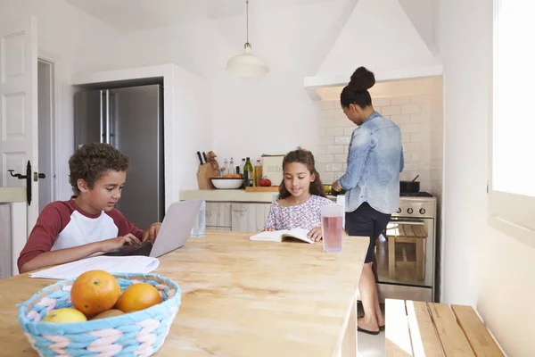 Mama kocht und Kinder lernen in der Küche — Stockfoto