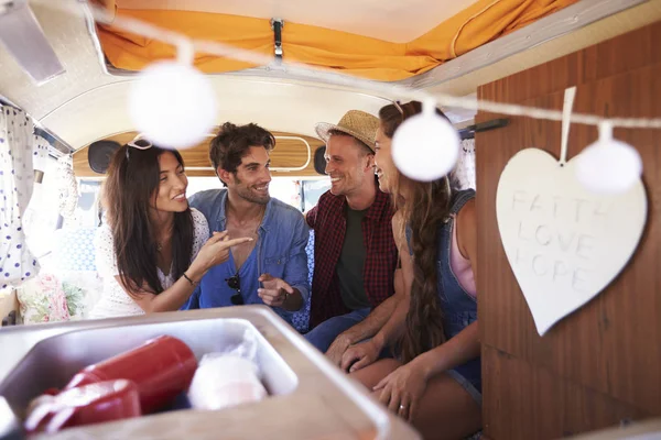 Cuatro amigos en un viaje por carretera hablan en la parte trasera de una caravana — Foto de Stock