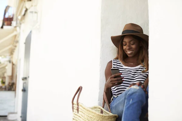 Woman sitting on steps and looking at phone — Stock Photo, Image