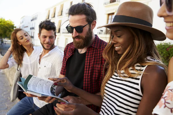 Freunde im Urlaub schauen sich Reiseführer an — Stockfoto