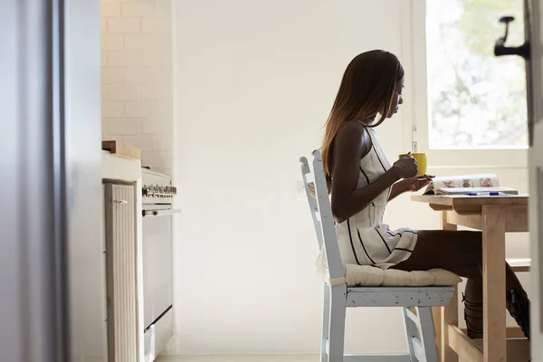 Молодая женщина читает на кухне — стоковое фото