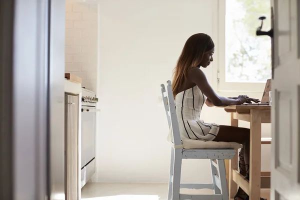 Mujer usando ordenador portátil en la cocina — Foto de Stock