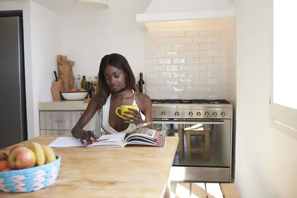 Young woman reading in kitchen — Stock Photo, Image
