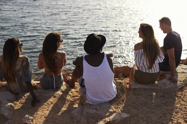 Amigos sentados en el acantilado viendo la puesta de sol —  Fotos de Stock