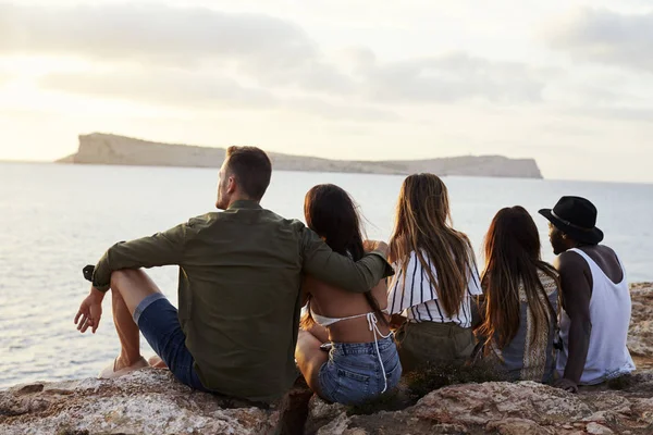 Amici seduti sulla scogliera a guardare il tramonto — Foto Stock