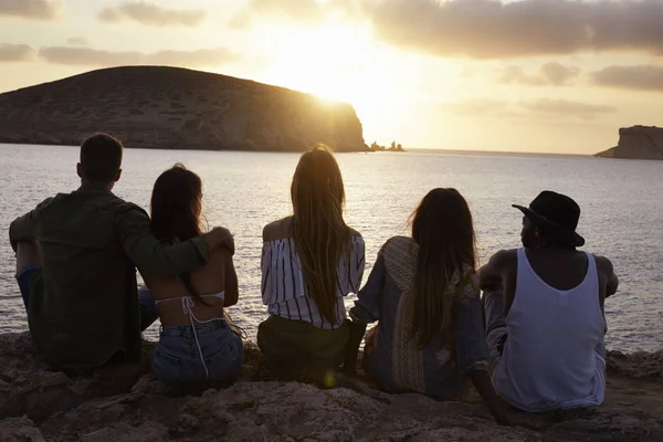 Amis assis sur la falaise regardant coucher de soleil — Photo