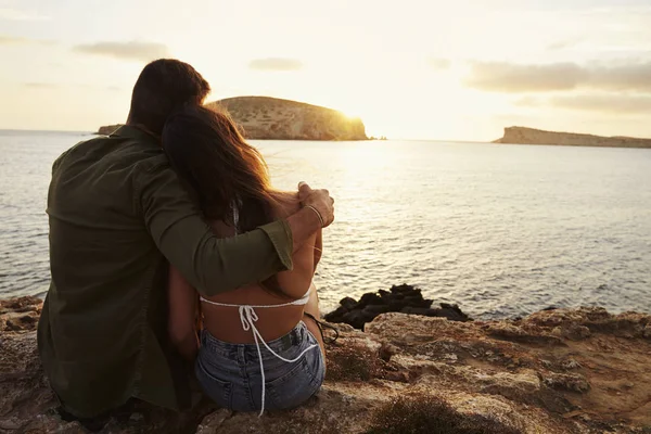 Pareja sentada en acantilado viendo atardecer — Foto de Stock