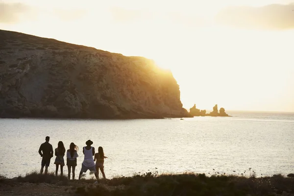 Amigos de pie en el acantilado viendo la puesta de sol — Foto de Stock