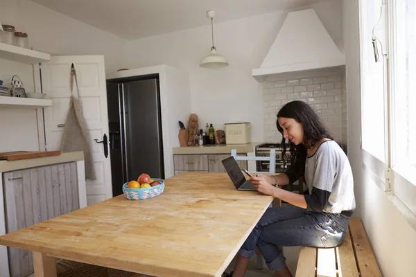 Flicka med laptop läsa meddelande på telefon — Stockfoto