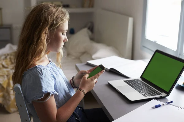 Dziewczyna za pomocą smartfona i siedzi przed laptop — Zdjęcie stockowe