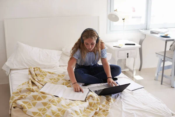 Mädchen liest Hausaufgaben und sitzt auf dem Bett — Stockfoto