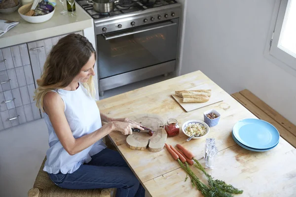 Женщина режет овощи за столом — стоковое фото
